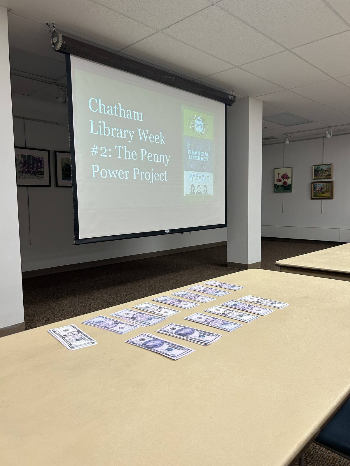 Penny Power Project slide projected at the Library of the Chathams with play money laid out on a table